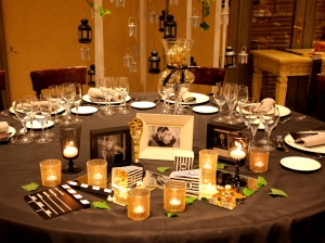 Mesa para boda en diseño cinéfilo con mantel gris oscuro, accesorio dorados, y retratos de actores vista angulo picado