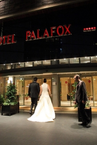 Recién casados en la entrada del hotel Palafox con vista normal cubiertos en la magia del hotel